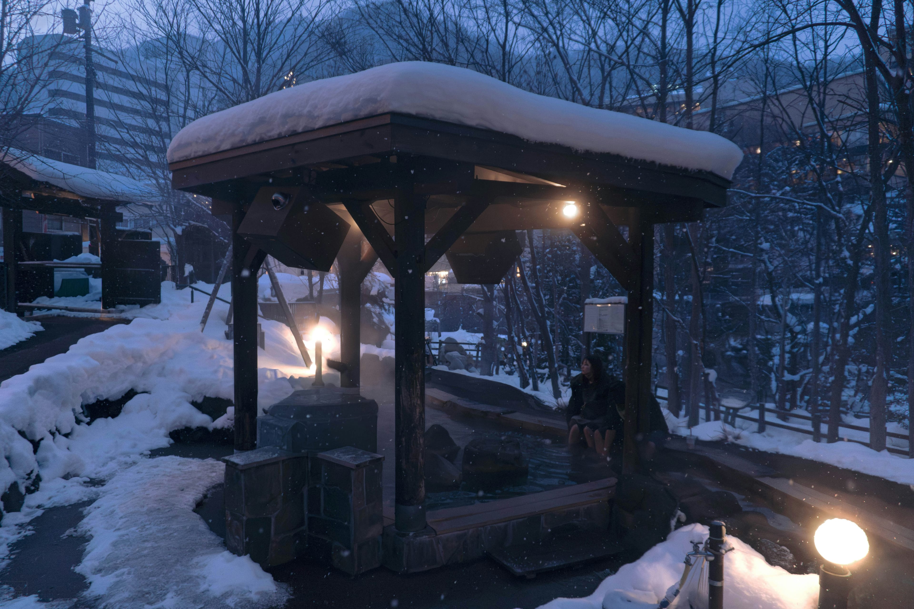 Snow falling on a peaceful outdoor hot spring